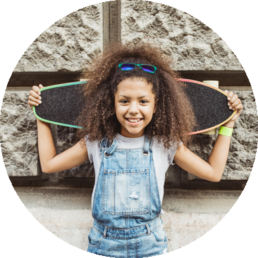 female child smiling and holding a skateboard